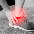 Runner touching painful twisted or broken ankle. Athlete runner training accident. Sport running ankle sprain.